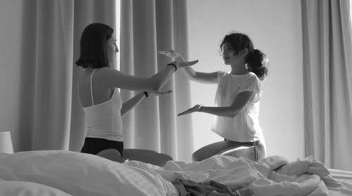 Young woman standing on bed at home