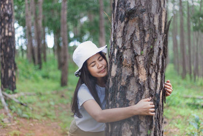 Young woman embracing tree trunk in forest