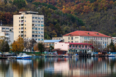 Buildings by lake against trees in city