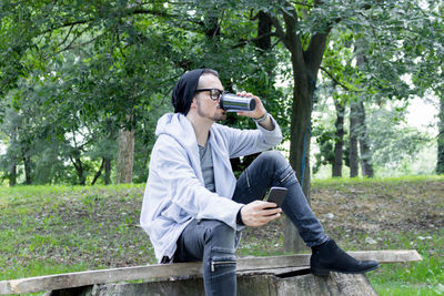 Mature man using smart phone while drinking coffee in park