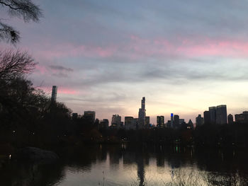 River by buildings against sky at sunset