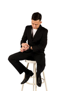Young man sitting on chair against white background