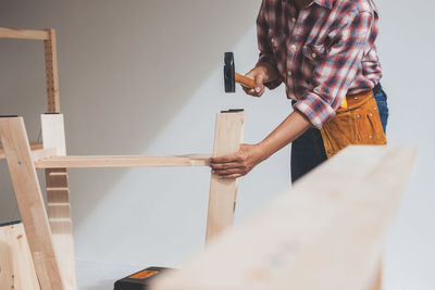 Man working on wood against wall at home