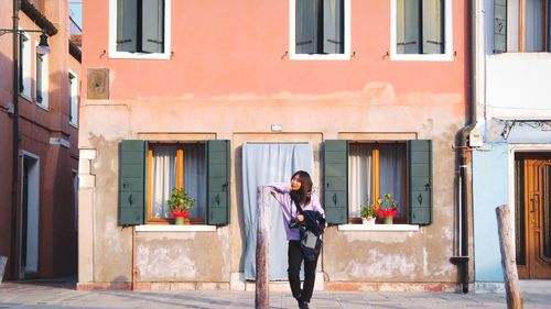 Full length of woman standing against building