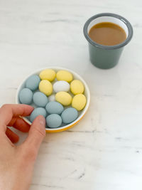 High angle view of hand holding eggs in bowl on table