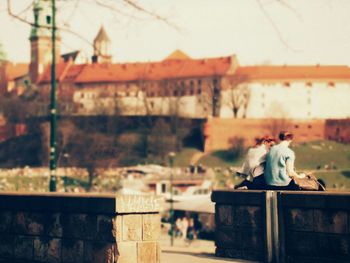 Rear view of woman sitting on table against wall