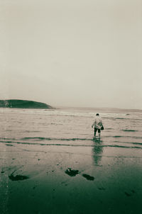 Rear view of man walking on beach