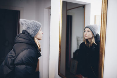 Woman looking at reflection in mirror on wall