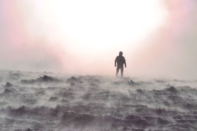 Silhouette man standing on land against sky during sunset