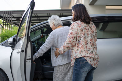 Rear view of woman standing in car