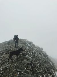 Rear view of man on rock against sky