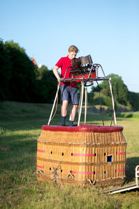 Man playing music while standing on built structure against clear sky