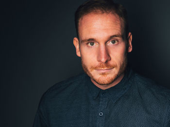 Close-up portrait of man against black background