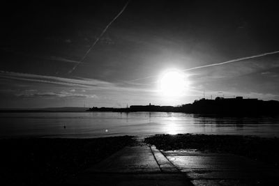 Scenic view of silhouette vapor trails against sky during sunset