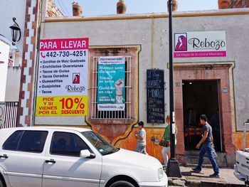 Information sign on street against buildings in city