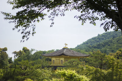 Built structure by trees and building against sky