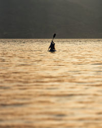 Silhouette man in sea against sky during sunset