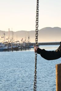 Man holding sailboat in sea against clear sky