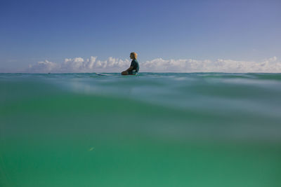 Side view of man in sea against sky