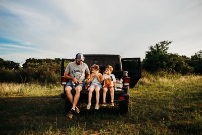 Dad and two kids having a picnic on truck tailgate