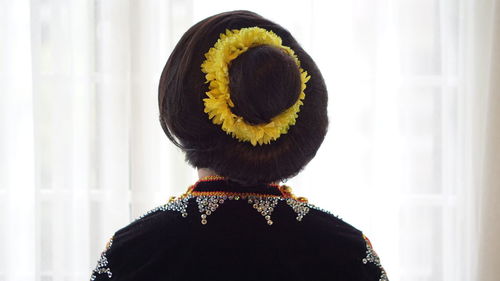 Rear view of woman standing against yellow wall