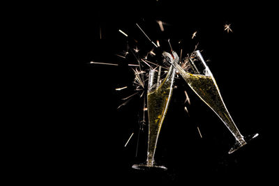 Digital composite image of firework display and drinks over black background