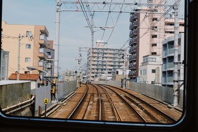 Railroad tracks and buildings seen through train window