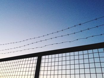 Low angle view of power lines against clear blue sky