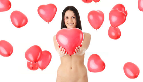 Portrait of woman with red balloons against white background