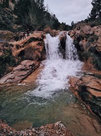 Scenic view of waterfall in forest against sky