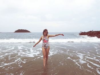 Full length of boy standing on beach against sky