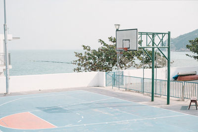 Empty swimming pool by sea against clear sky