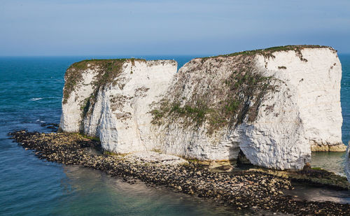 Rock formation in sea against clear sky