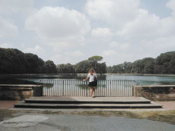 Rear view of woman standing by pond