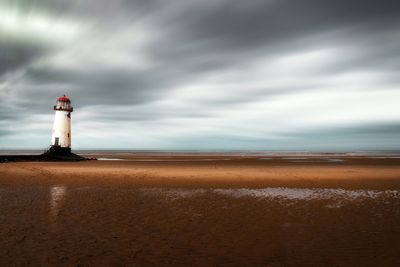 Lighthouse by sea against sky