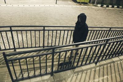 Rear view of woman standing on railing