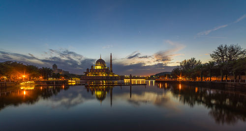 Illuminated putra mosque reflecting in putrajaya lake against sky