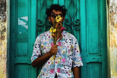 Man with flowers standing against door