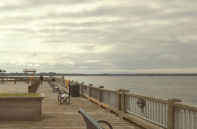 Pier on sea against cloudy sky