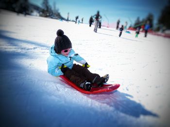 Girl tobogganing on snowy land