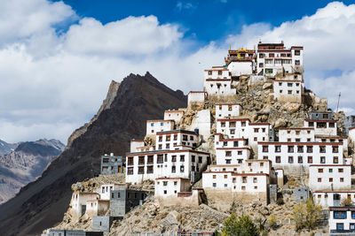 Houses on mountain against cloudy sky