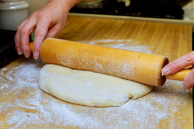 Cropped hands of woman rolling pin on dough