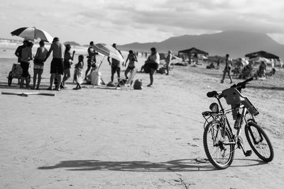View of beach with bicycle and people against sky
