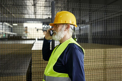 Mature worker on cell phone in factory warehouse
