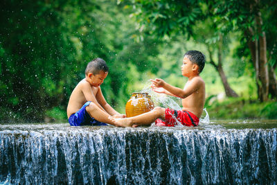 Full length of shirtless boy sitting in water