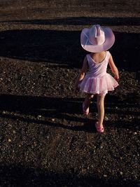 Rear view full length of girl in hat walking on field