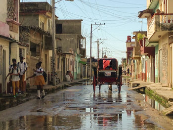 People on wet street amidst buildings in city