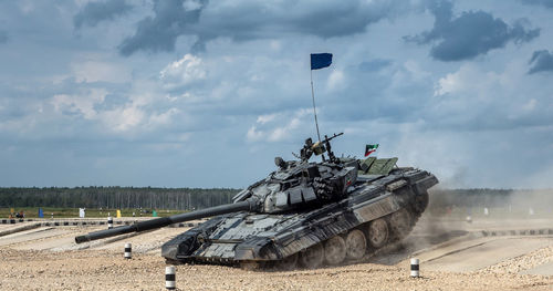 Tank moving at patriot park against cloudy sky