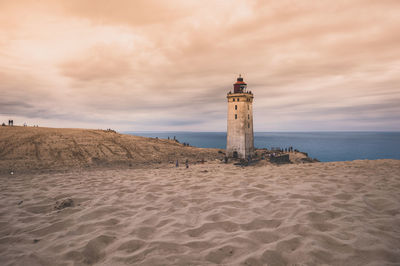 Lighthouse on beach against sky