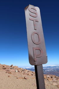Low angle view of an old, rusted stop sign board against clear blue sky at the top of pikes peak, co 